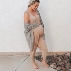 Pregnant mom wearing a Momper Romper jumpsuit in taupe.